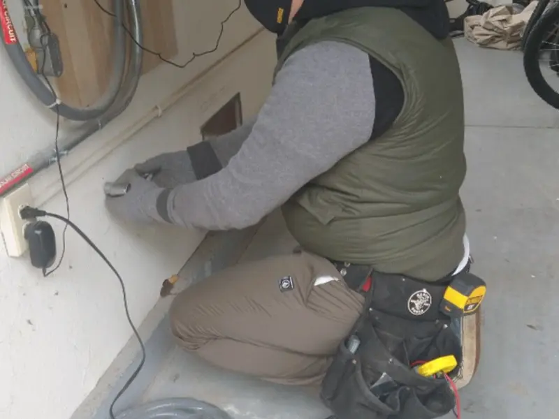 Electrician performing outlet wiring in a Wayne garage